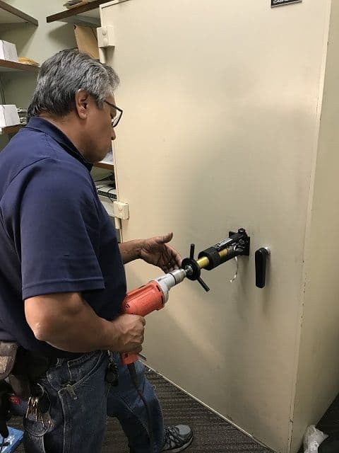 A technician drilling a lost-key safe deposit box
