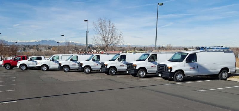 The M.R. Solutions van fleet: white vans and a red pickup in a parking lot
